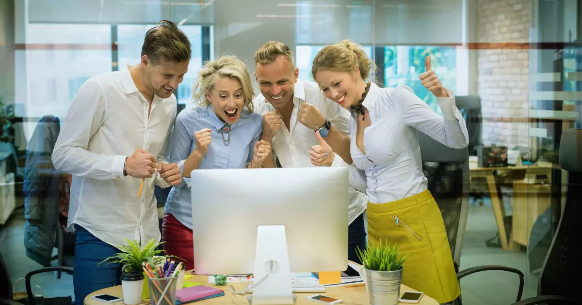 Team celebrating around a computer after achieving growth and online success with website management service