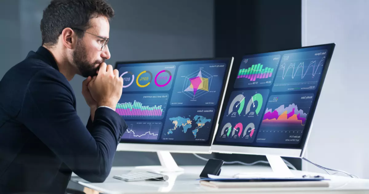 A person looking at multiple computer screens with graphs