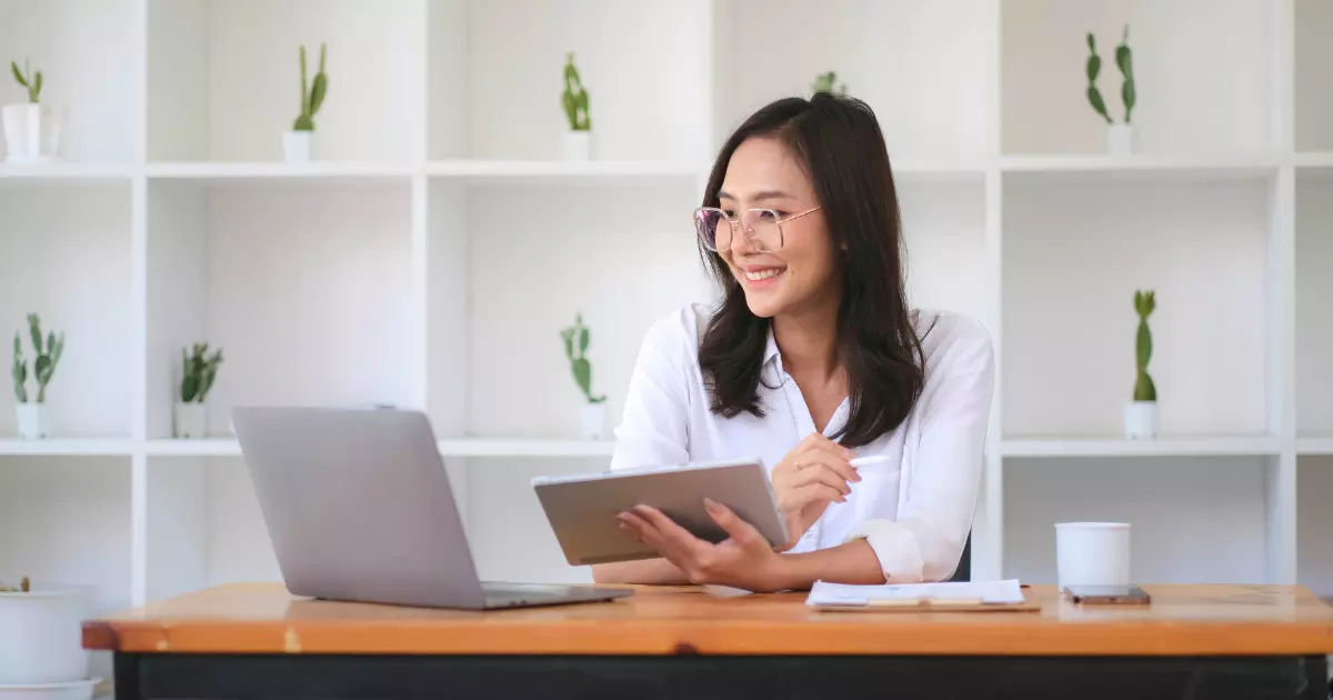 A person sitting at a desk with a computer and a tablet