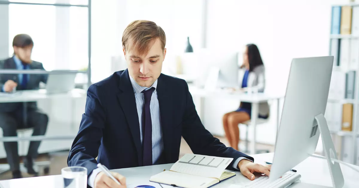 A person in a suit writing on a book