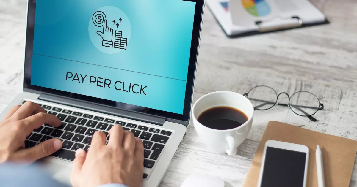 A hand typing pay per click on a laptop
