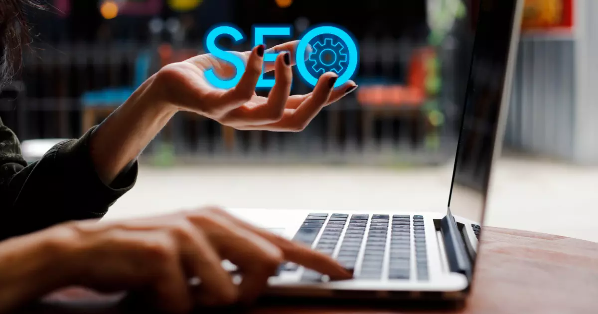 A close up of a person using a laptop with the glowing word SEO hovering over their hand symbolizing the power of search engine optimized content