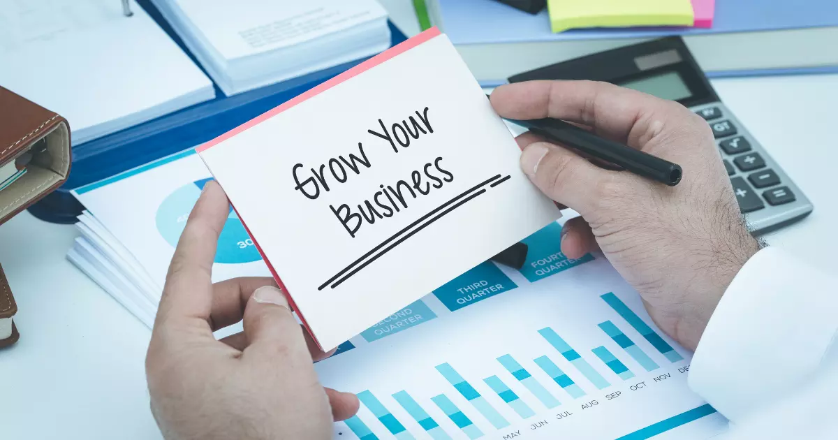 A close up of hands holding a card that says Grow Your Business emphasizing organic growth through strategic planning