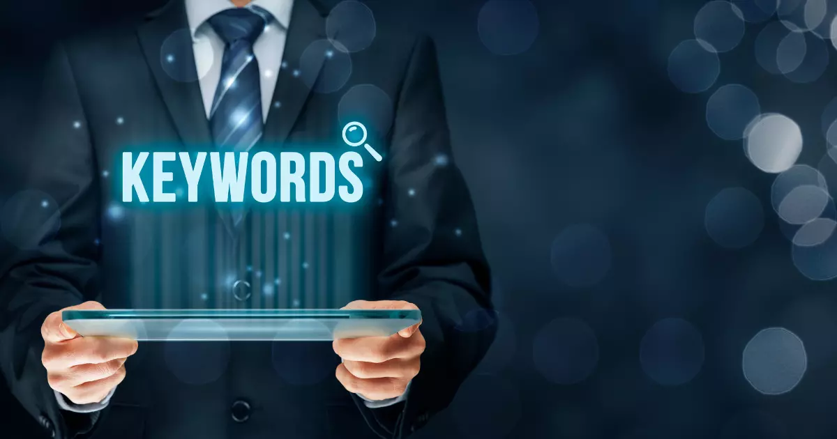 A man in a suit holds a digital tablet with the word KEYWORDS illuminated above it symbolizing the significance of long tail keywords in online marketing strategies