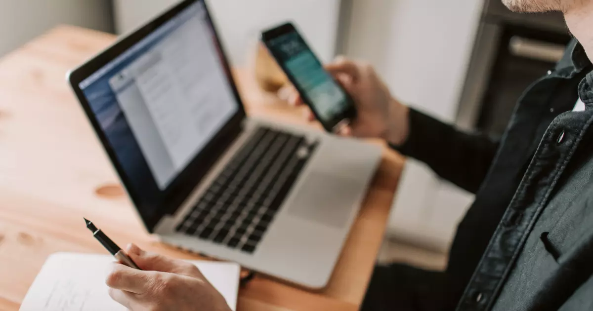 Man using phone and laptop for online marketplace tasks